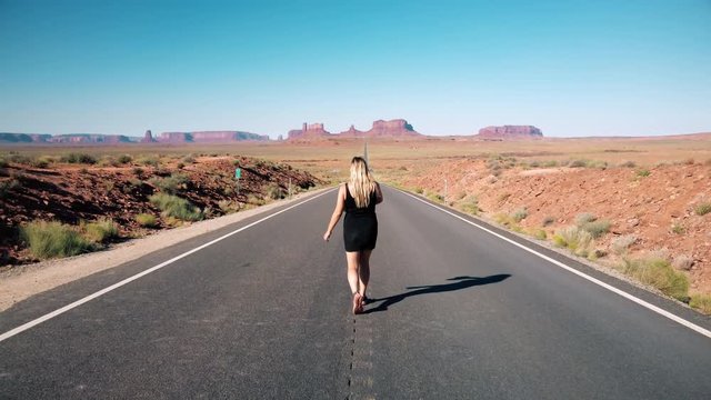 Young dusty blonde girl throws cowboy hat on Forrest Gump Point Road to Monument Valley, region of Colorado Plateau buttes Arizona&ndash;Utah border. Slow motion Gimbal panning cinematic Rec.709 ProRes 422