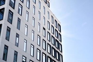 Modern European building. White building with many windows against the blue sky. Abstract architecture, fragment of modern urban geometry.