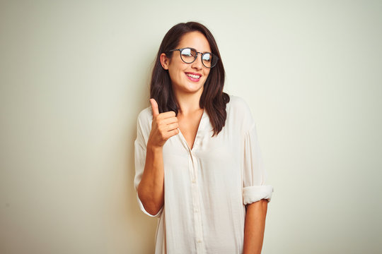 Young beautiful woman wearing shirt and glasses standing over white isolated background looking to side, relax profile pose with natural face with confident smile.