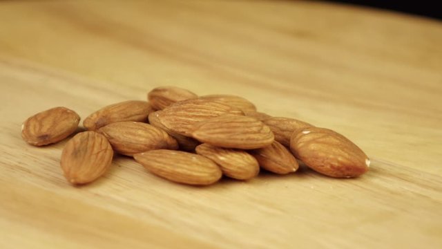 a handful of almonds rotates 360 degrees on a wooden platform