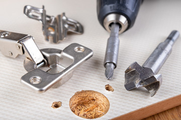 Installation of furniture hinges in the kitchen cabinet door. Tools and furniture accessories...