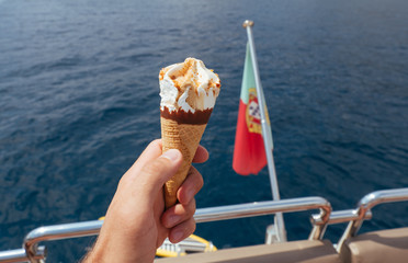 Ice cream in a waffle cup in man's hand on the yacht