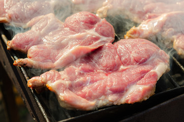 Cooking pork steak on a portable metal grill. Grill pork steak barbecue.