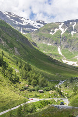 Austrian Alps. Snowy mountain peaks. Mount Grossglockner. The majesty of nature. Alpine road. Mountain landscape. Green grass in the hills. Forests among the rocks. Hiking in Europe.