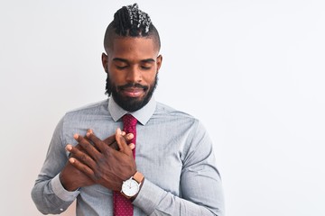 African american businessman with braids wearing tie standing over isolated white background smiling with hands on chest with closed eyes and grateful gesture on face. Health concept.