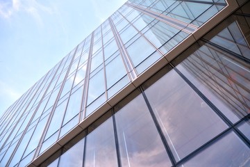 Obraz premium Modern office building wall made of steel and glass with blue sky