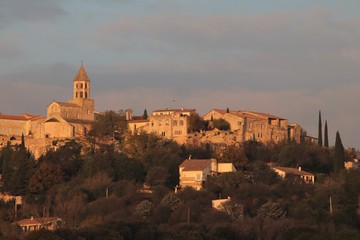 Naklejka premium La Garde Adhémar - Village typique de la Drôme provençale vu depuis la route en contrebas au soleil couchant