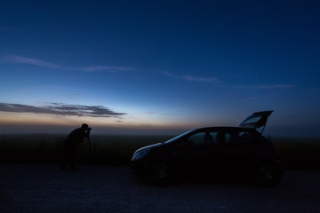 photographer with the car in the field, night, backlight