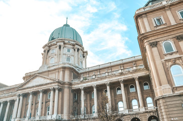 Fototapeta na wymiar Buda Castle in Budapest, Hungary with light blue sky above. Historical castle and palace complex of the Hungarian kings. Facade with pillars, balconies and cupola. Tourist landmark