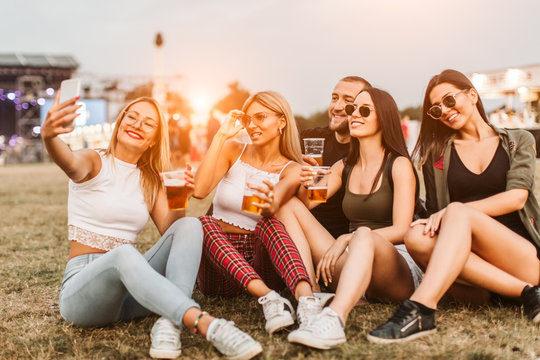 Group of happy friends taking selfie at music festival