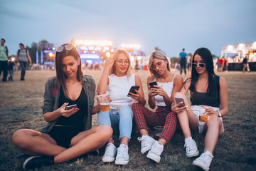 Four girls using their phones at the music festival