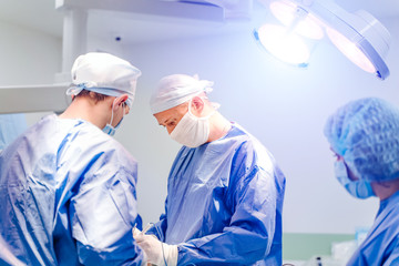 Group of surgeons in operating room with surgery equipment. Medical background