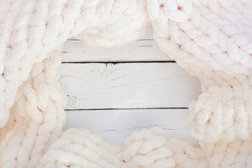 Cozy knitted thick wool blanket. Top view frame on a white wood background with copy space. Cream...