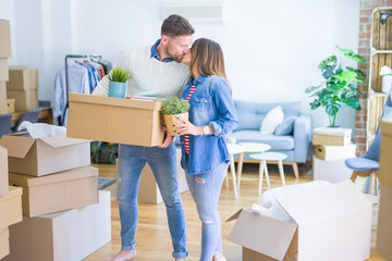 Fototapeta na wymiar Young beautiful couple moving cardboard boxes and kissing at new home