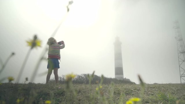 Little girl on holidy makes a pisture of a lighthouse in the mist