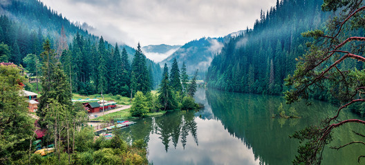 Panoramic morning view of Lacu Rosu lake. Misty summer scene of Harghita County, Romania, Europe. Beauty of nature concept background. - obrazy, fototapety, plakaty