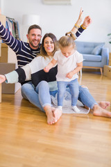 Fototapeta na wymiar Beautiful family sitting on the floor playing with his kid at new home around cardboard boxes