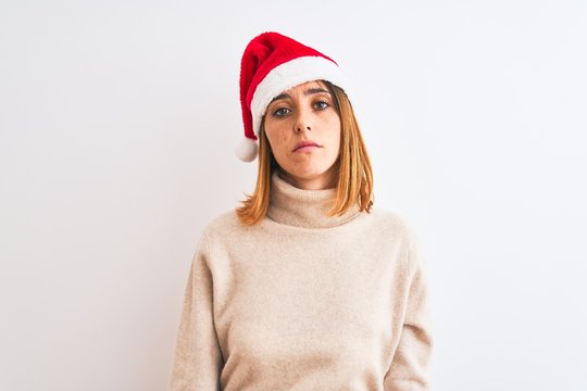 Beautiful redhead woman wearing christmas hat over isolated background looking sleepy and tired, exhausted for fatigue and hangover, lazy eyes in the morning.