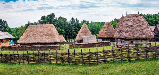 Fototapeta na wymiar Panoramic summer view of traditional romanian peasant houses. Captivating rural scene of Transylvania, Romania, Europe. Beauty of countryside concept background.