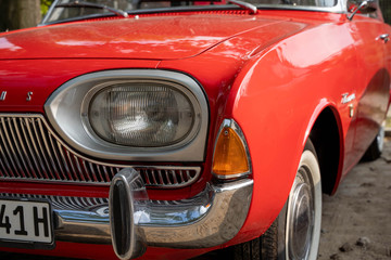 Obraz na płótnie Canvas Detail of front light of a red vintage retro automobile (shallow depth of field)