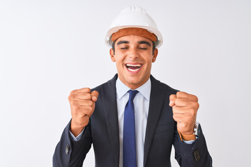 Young handsome architect man wearing suit and helmet over isolated white background excited for success with arms raised and eyes closed celebrating victory smiling. Winner concept.