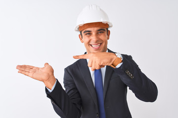 Young handsome architect man wearing suit and helmet over isolated white background amazed and smiling to the camera while presenting with hand and pointing with finger.