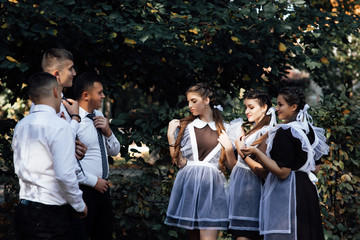 Having fun and divided into two teams of boys and girls. Group of teens in school uniform that is outdoors posing for photography. Friends studying in one class.