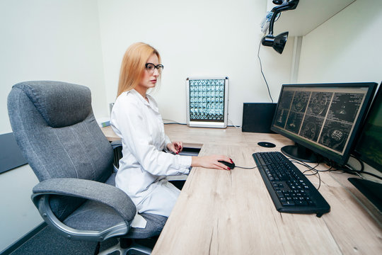 Young blonde doctor typing on computer and examine MRI picture
