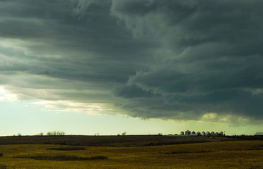 Stormy cky over a rural field and grain bins