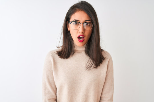 Chinese woman wearing turtleneck sweater and glasses over isolated white background scared in shock with a surprise face, afraid and excited with fear expression