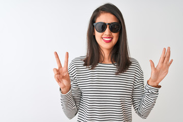 Chinese woman wearing striped t-shirt and sunglasses standing over isolated white background...