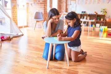 Beautiful teacher and toddler girl drawing draw using digital board at kindergarten