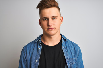 Young handsome man wearing denim shirt standing over isolated white background with a confident...