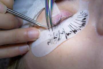 Extension of long eyelashes in a beauty salon. Wizard combing eyelash client