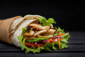 Tasty doner kebabs with fresh salad trimmings and shaved roasted meat served in tortilla wraps on brown paper as a takeaway snack