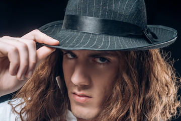 Young handsome man emotional pose with hat. Portrait of handsome young serious confident young guy with long hair in hat. Man with confident face and brutal style. Barbershop advertising.