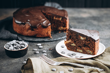 Traditional italian chocolate cake with apples and cinnamon on a dark background