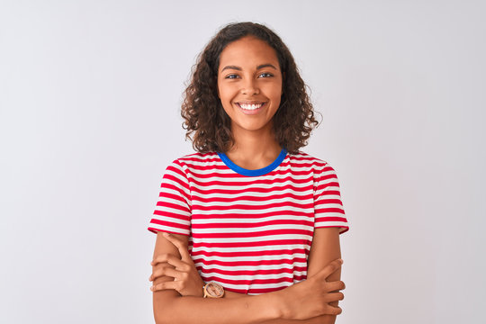 Young brazilian woman wearing red striped t-shirt standing over isolated white background happy face smiling with crossed arms looking at the camera. Positive person.