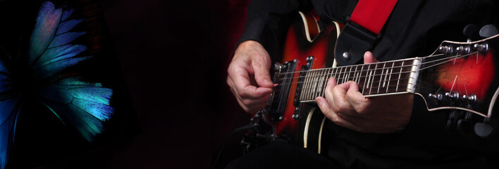 Blues music concept. Playing the blues. Guitarist hands and guitar on a black background and blue...