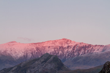 Peak of Mount Snowdon lit by sunset