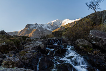 Early morning light and shadow over mountains and snow. Glyder Farw. Waterfall on stream. Landscape