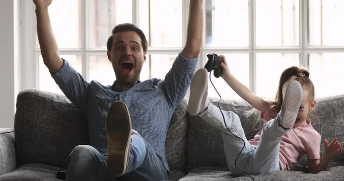 Funny excited dad and child daughter playing videogame celebrating victory