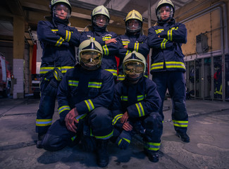 Portrait of group firefighters in front of firetruck inside the fire station