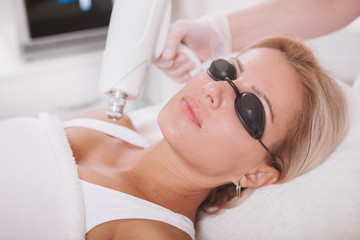 Cropped shot of a professional cosmetologist removing skin pigmentation on the shoulder of female...