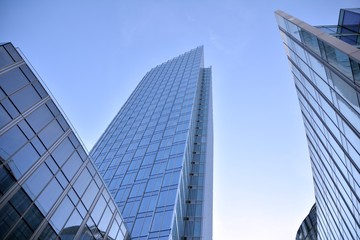 Modern office building wall made of steel and glass with blue sky