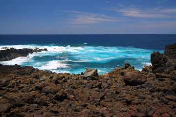 Fototapeta na wymiar The intense blue sea and the black volcanic rocks