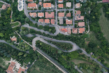 Fototapeta premium Overhead aerial drone shot of winding mountain road with streets to Castel San Pietro in Verona, Italy
