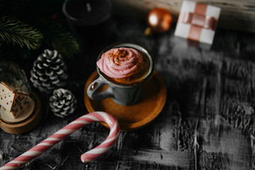 Coffee, pink marshmallow, fir branch, pine cone, gift box, candy cane on dark backdrop. For Christmas, new year winter holiday drink, beverage. Festive template, copy space, shallow depth of field