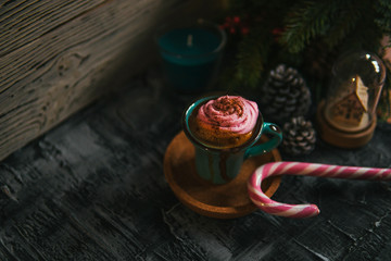 Coffee, pink marshmallow, fir branch, pine cone, candy cane on dark rustic backdrop. For Christmas, new year winter holiday drink, beverage. Festive template, copy space, shallow depth of field