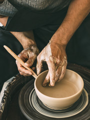 Ceramist at a pottery workshop Man is sculpting a bowl behind a rotating potter's wheel - obrazy, fototapety, plakaty